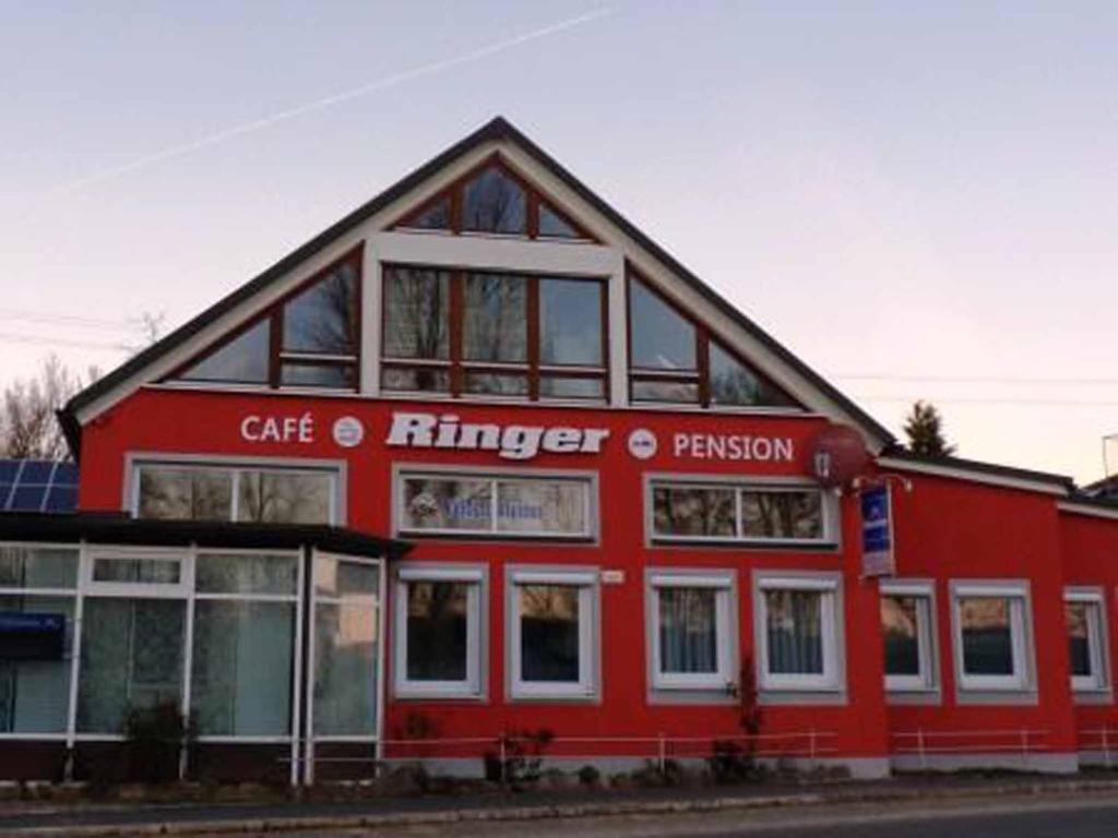 VilseckCafe und Pension Ringer的一座红色的建筑,前面有标志