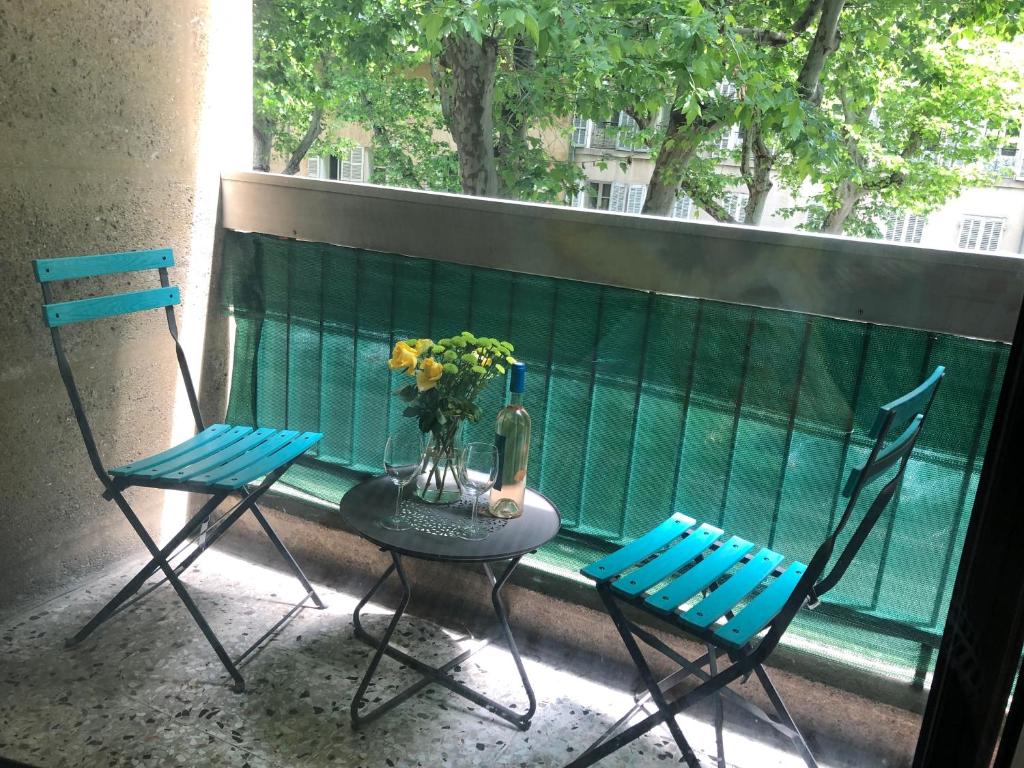 普罗旺斯艾克斯Aix Homes的阳台上配有两把椅子和一张桌子,花瓶上放着鲜花