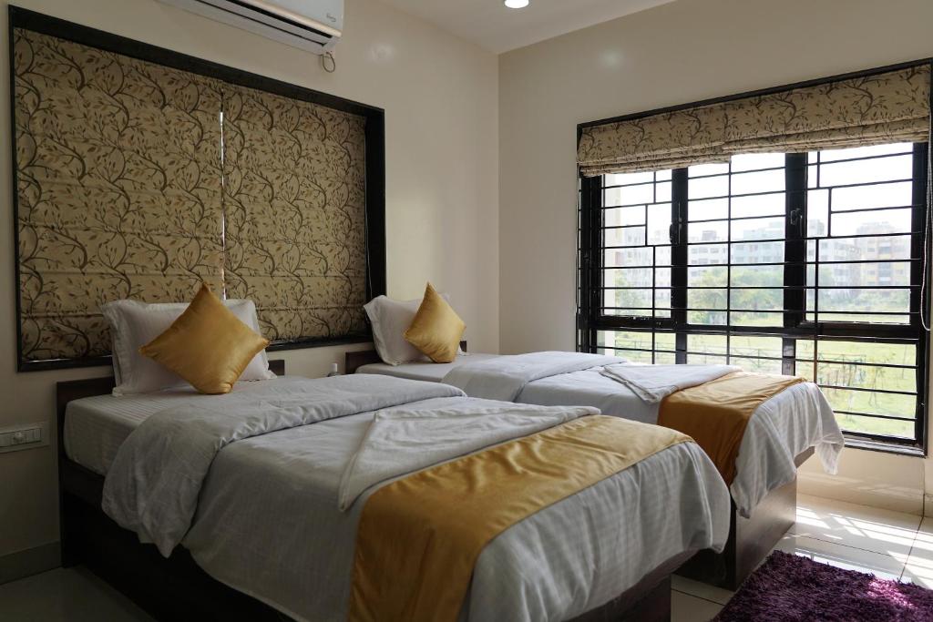 加尔各答Rama Golden Root New town的带2扇窗户的客房内的2张床