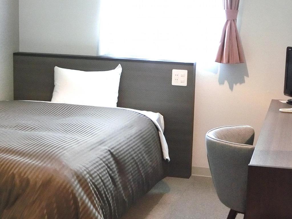 仙台仙台东橘子酒店的一间卧室配有一张床、一张桌子和一把椅子