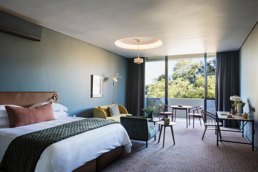 约翰内斯堡Home Suite Hotels Rosebank的酒店客房带一张床、一张桌子和椅子