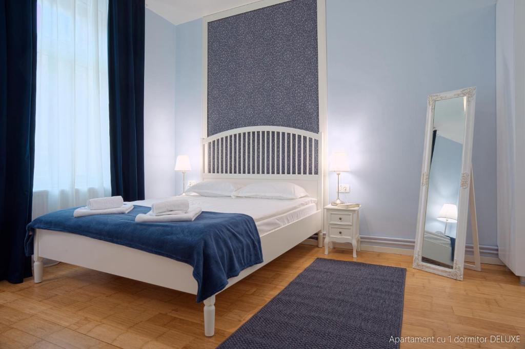 布拉索夫Republicii Residence的一间卧室配有一张带蓝色毯子和镜子的床