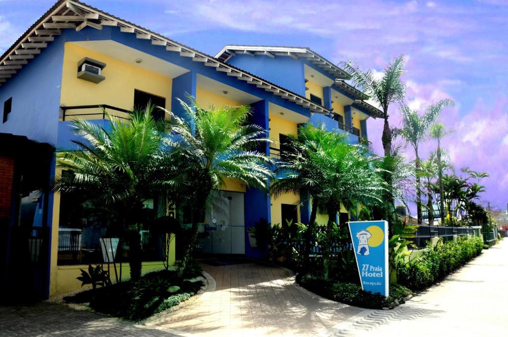 伯迪亚哥27 Praia Hotel - Frente Mar的一座蓝色和黄色的建筑,前面有棕榈树