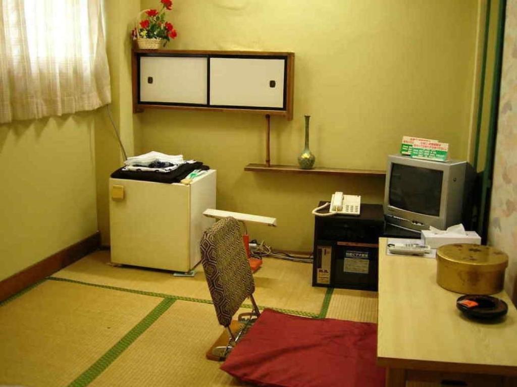今治市Komecho Ryokan / Vacation STAY 33206的客房设有书桌、冰箱和电视。