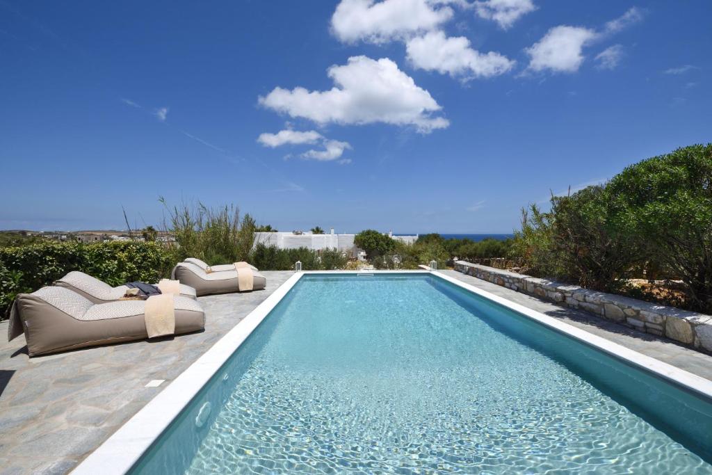 安倍拉斯Amalgam Homes Paros的一个带2把躺椅的游泳池和一个游泳池