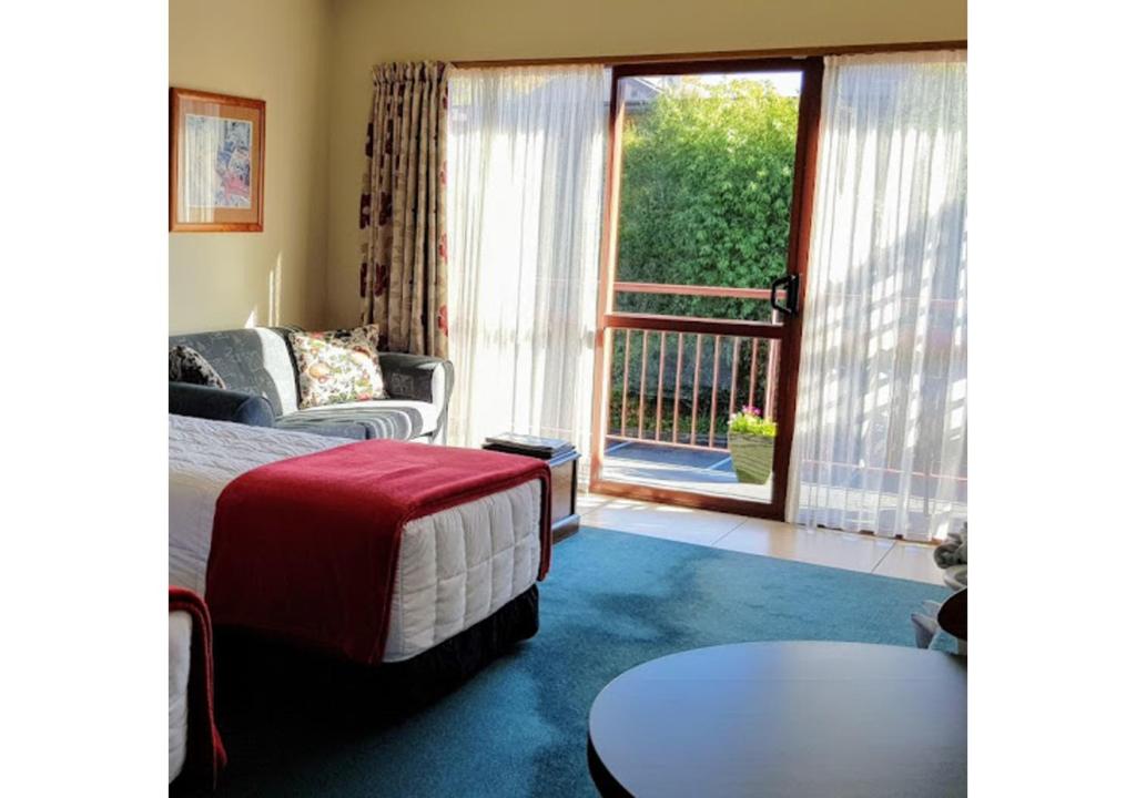 汉默温泉阿斯本汽车旅馆的一间卧室配有一张床、一张桌子和一个窗户。