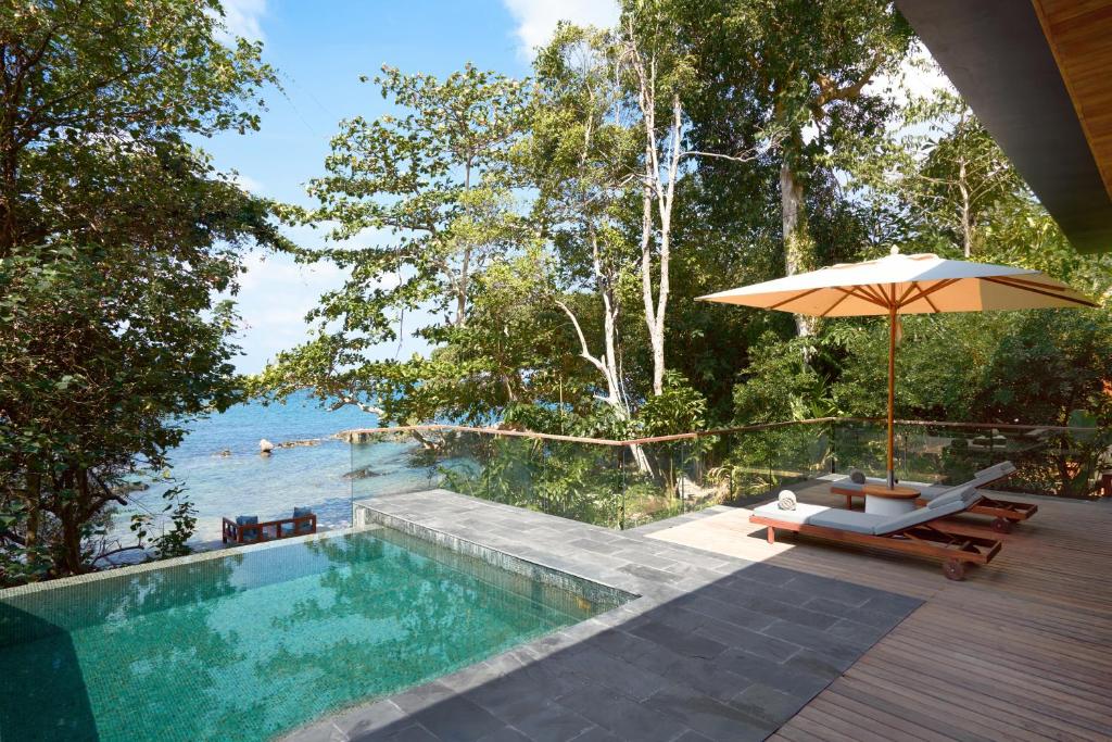 Koh Krabey克拉贝岛六善酒店的一个带遮阳伞和桌椅的游泳池
