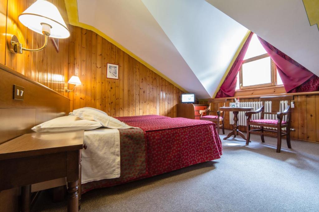 普雷圣迪迪埃Hotel Beau Sejour Pré-Saint-Didier的卧室配有一张床和一张桌子及椅子