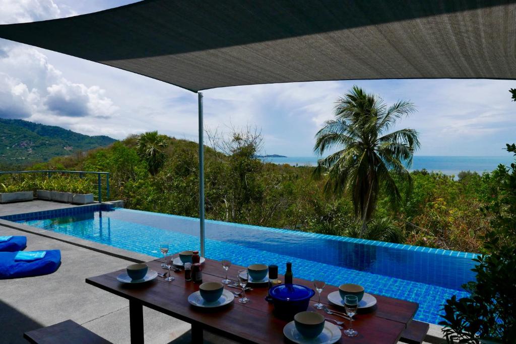 蓝赛特海滩Sky Villas Philippa with Free Car的享有游泳池景致的餐桌