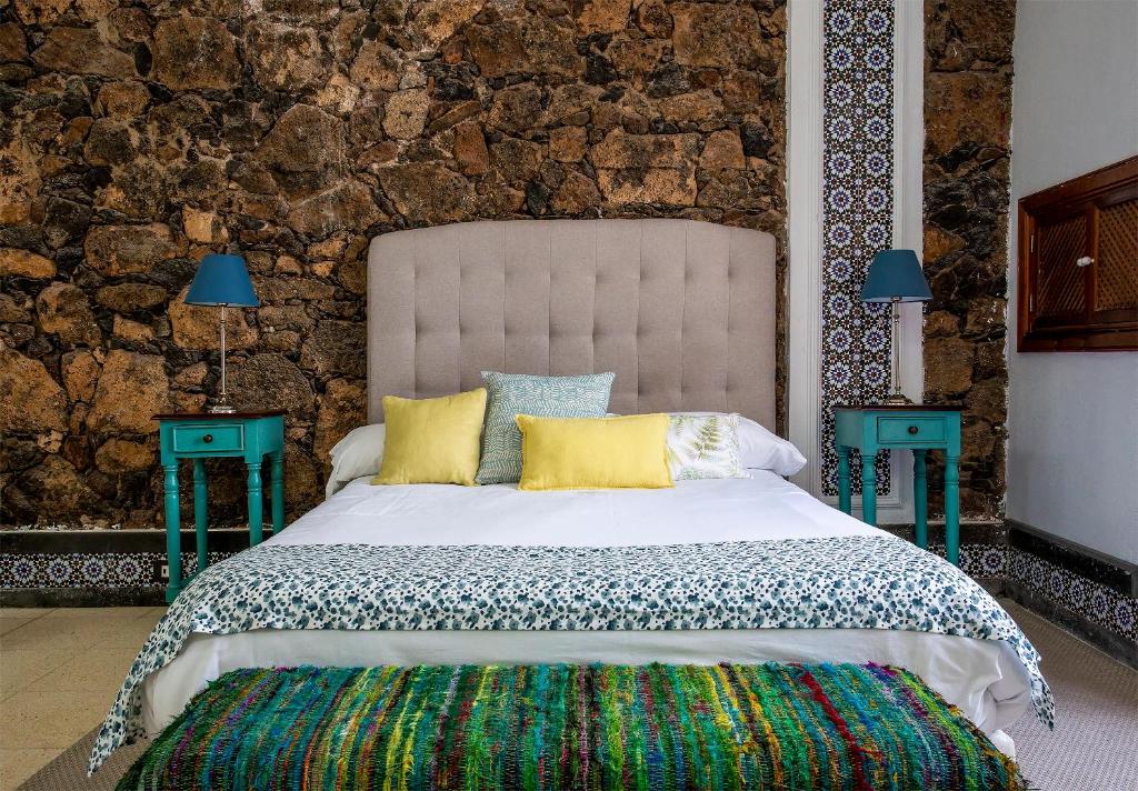阿雷西费El Charco Suites的一间卧室配有一张大床和两张蓝色的桌子