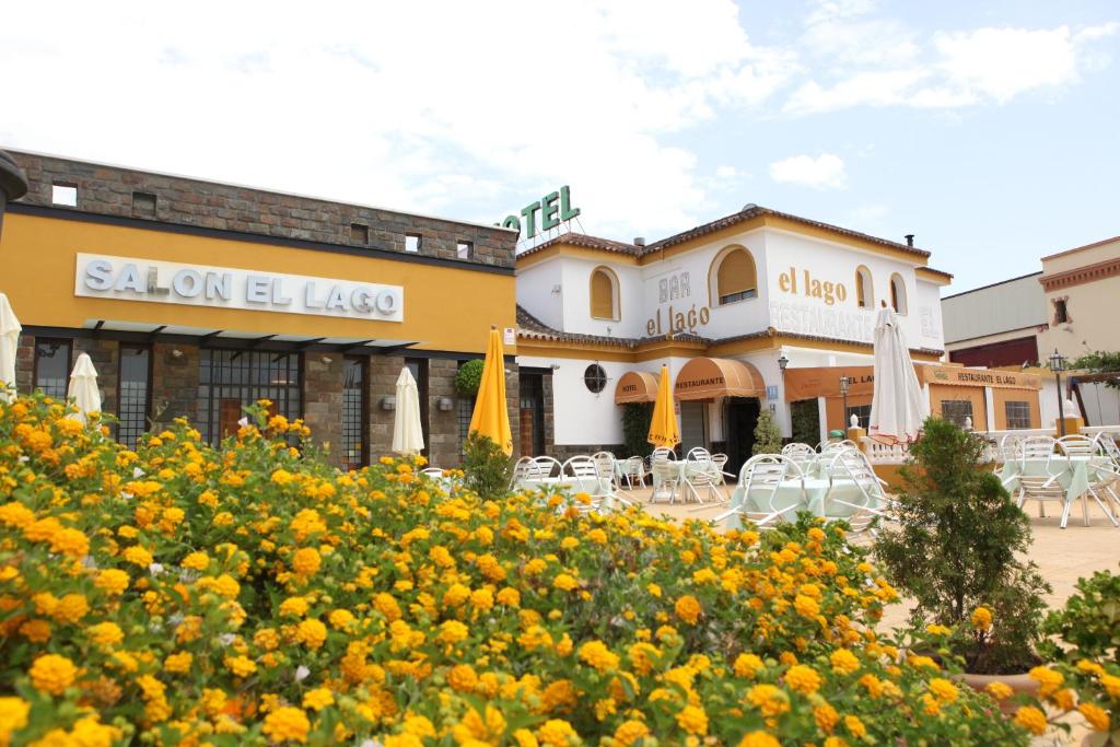 阿尔科斯-德拉弗龙特拉艾尔拉戈湖滨餐厅酒店的一座配有桌椅的建筑,鲜花黄色