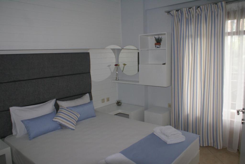 阿莫利亚尼岛Nostos Rooms Ammouliani的一间卧室配有一张带蓝色枕头的床和一扇窗户。