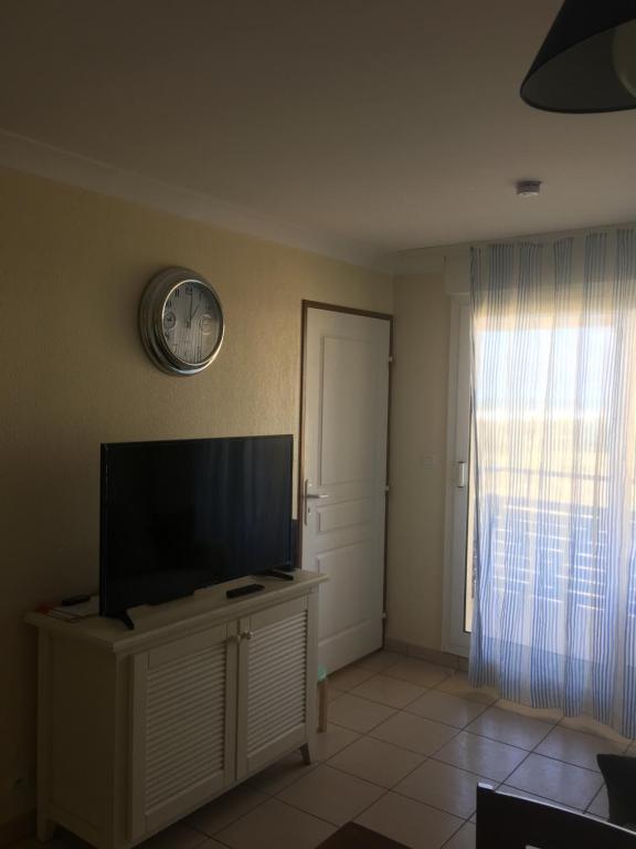 拉卡诺Bleu marine的客厅配有电视和墙上的时钟