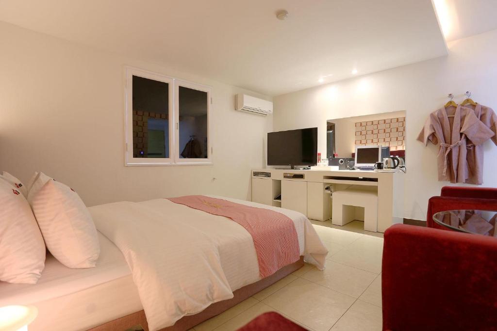 坡州市Q酒店的白色卧室配有床和书桌