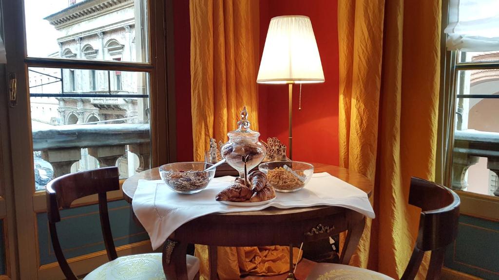 博洛尼亚Palazzo di Alcina - Residenza d'Epoca - Luxury-的窗户前的桌子上放着一碗食物