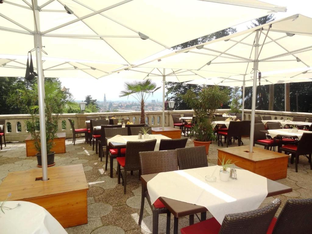 克拉根福斯维瑟豪斯酒店餐厅的一间设有白色遮阳伞和桌椅的餐厅