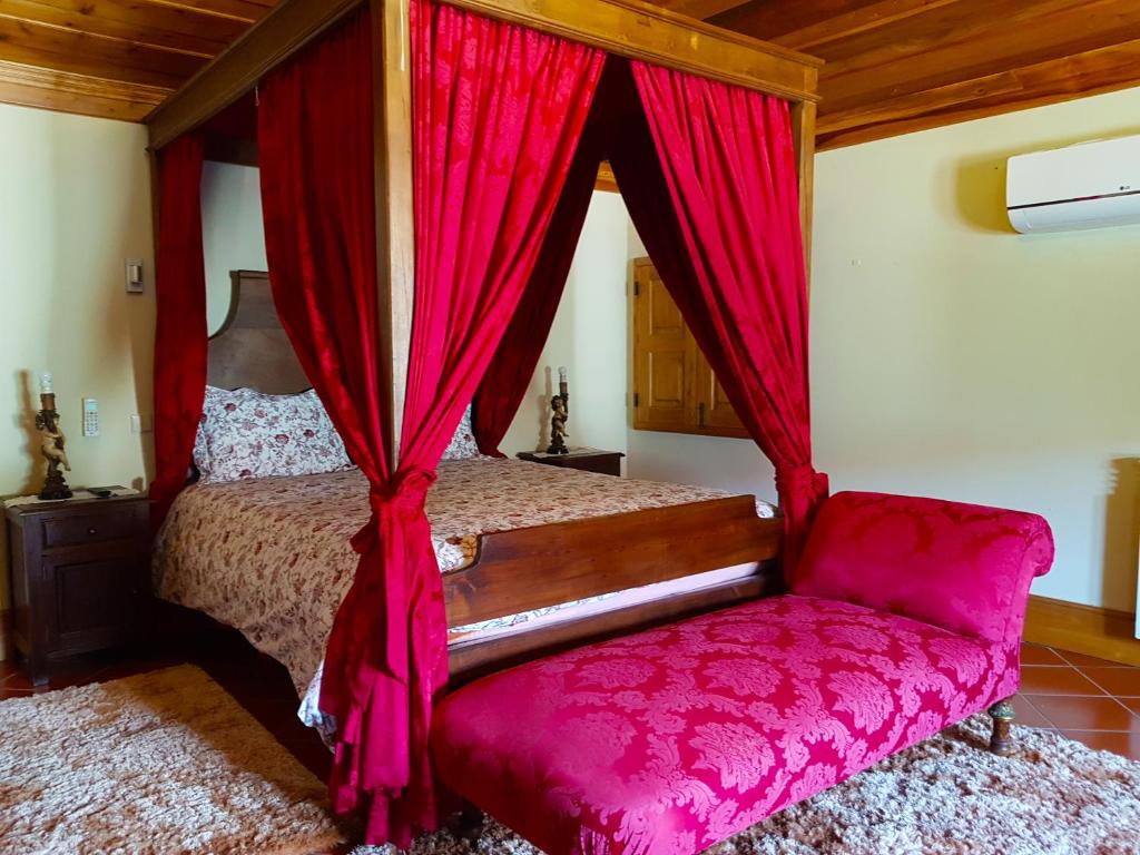 维埃拉·多米尼奥佩尼拉乡村民宿的一间卧室配有一张带红色窗帘的床和一把椅子
