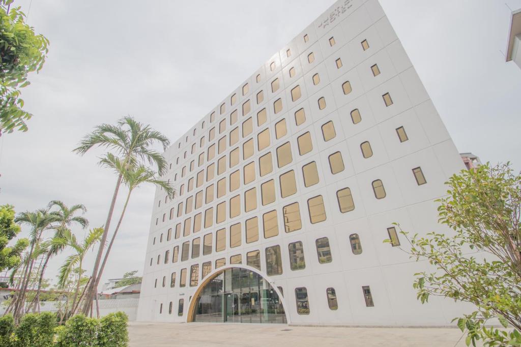 曼谷Justice Hotel的一座大型白色建筑,拥有棕榈树