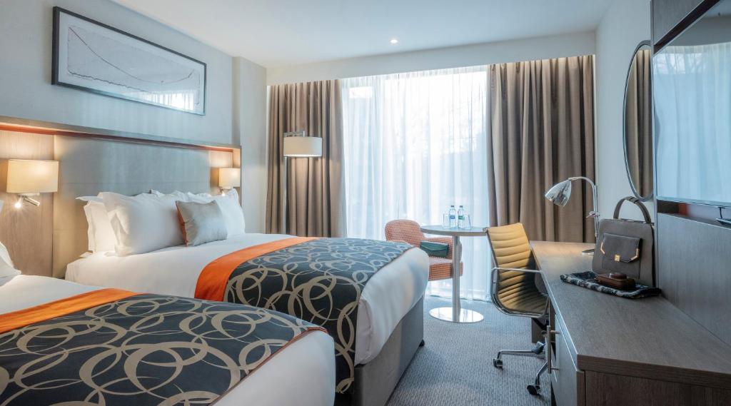 都柏林Clayton Hotel Charlemont的酒店客房配有两张床和一张书桌