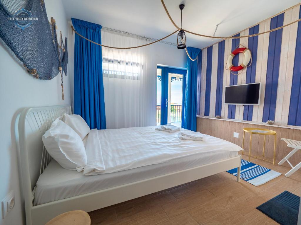 旧瓦马The Old Border的一间卧室配有一张带蓝色窗帘的床和电视。