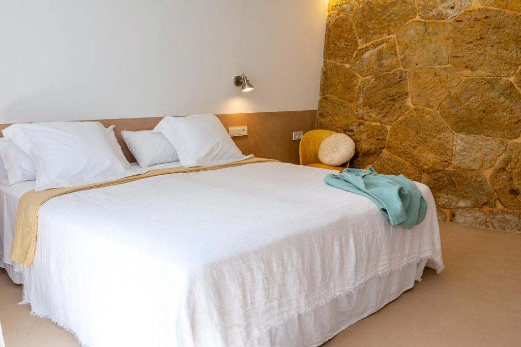 费雷列斯Noualt的卧室配有一张白色大床和石墙