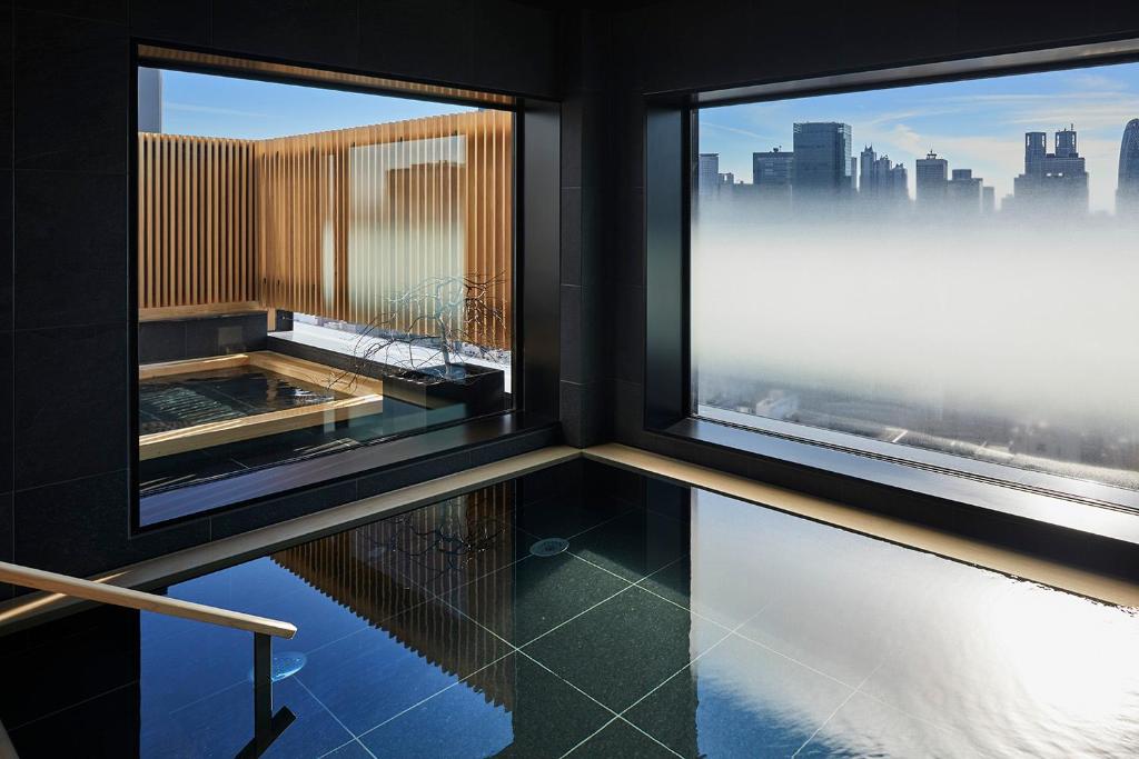 东京ONSEN RYOKAN YUEN SHINJUKU的客房设有2扇窗户,享有城市美景。