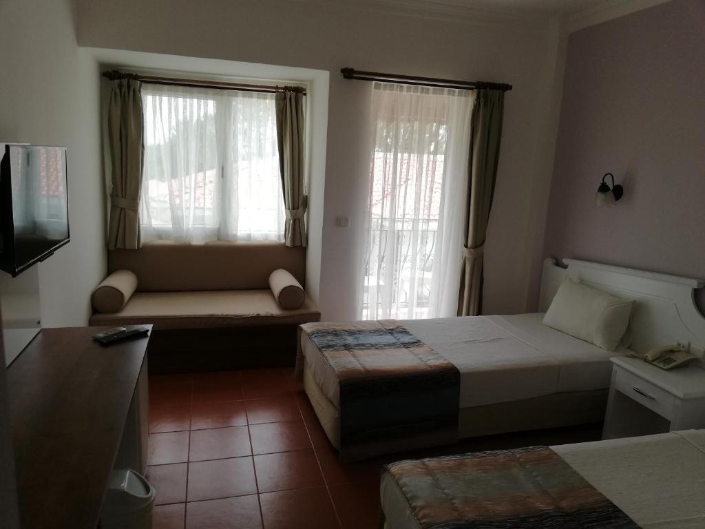 厄吕代尼兹卡贝尔海滩酒店的一间卧室配有一张床、一张沙发和两个窗户。