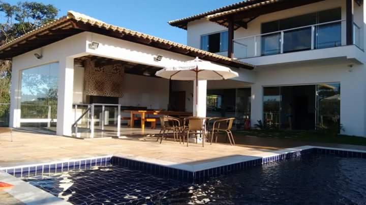 卡皮托利乌CASA UTOPIA ESCARPAS do LAGO的一座带游泳池、桌子和遮阳伞的房子