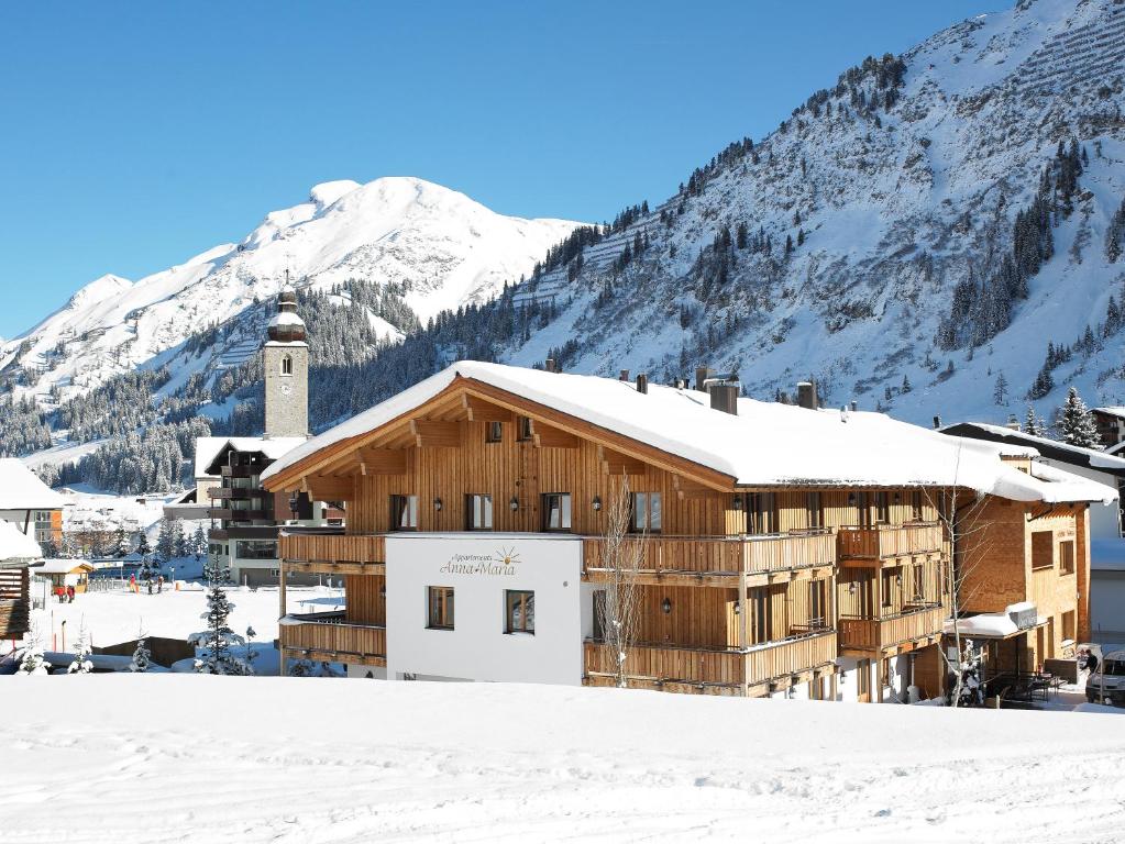 莱赫阿尔贝格Chalet Anna Maria的一座雪地中的建筑,背景是一座山