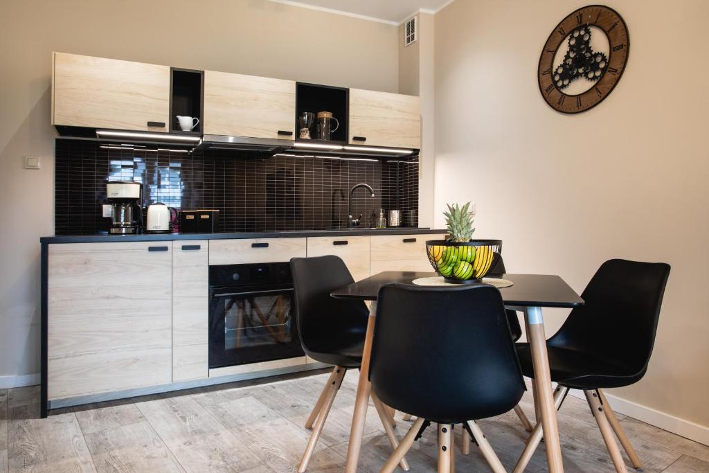波别罗沃Apartamenty Silence Baltic Classic的厨房配有黑色椅子、桌子和时钟