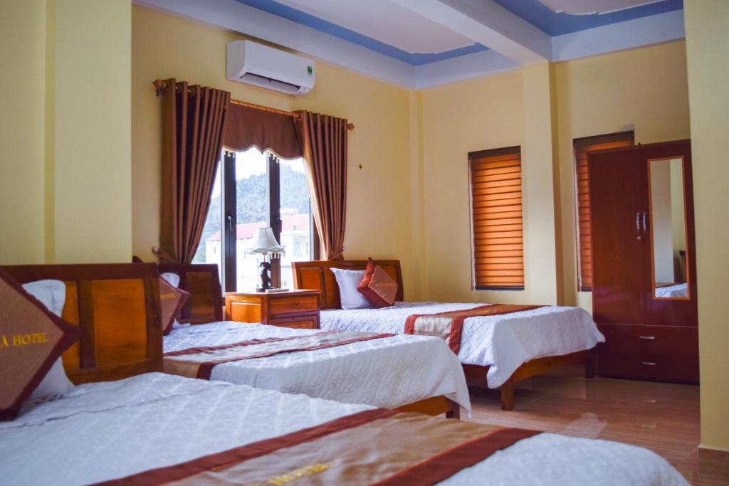峰牙Phong Nha Orient Hotel的酒店客房设有三张床和窗户。