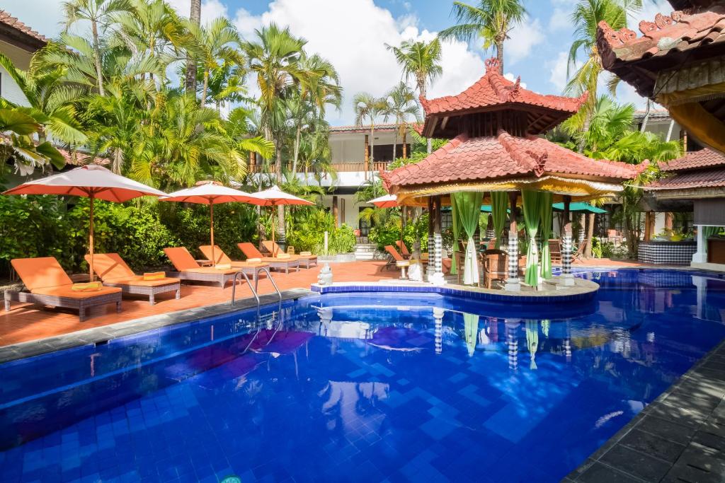 塞米亚克Sarinande Hotel的度假村的游泳池,配有椅子和遮阳伞