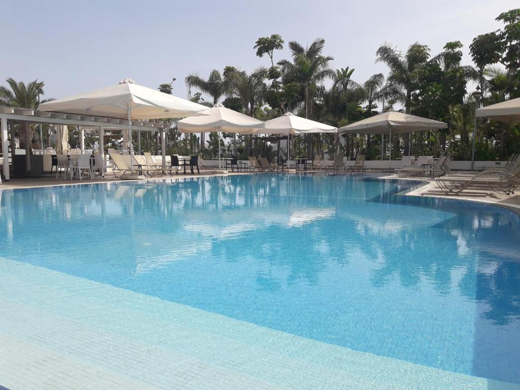 阿依纳帕卡萨纳帕公寓的一个带遮阳伞和椅子的大型蓝色游泳池