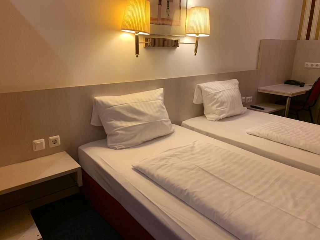 慕尼黑慕尼黑新贸易展览会议中心酒店的配有2张床铺的酒店客房,提供白色床单和枕头