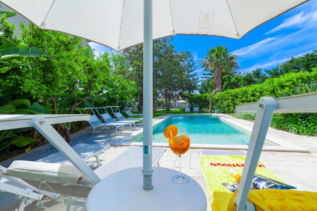 加利波利Relais Regina Rosanna的一个带遮阳伞和游泳池的庭院