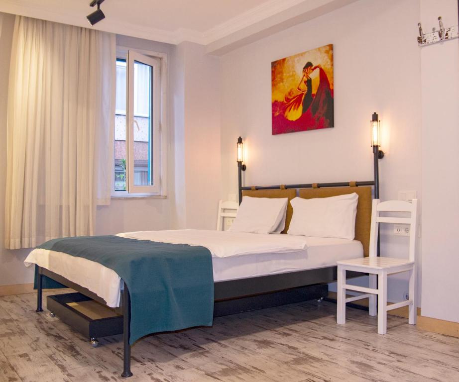 伊斯坦布尔热情实惠奥塔克依酒店的卧室配有一张床,墙上挂有绘画作品