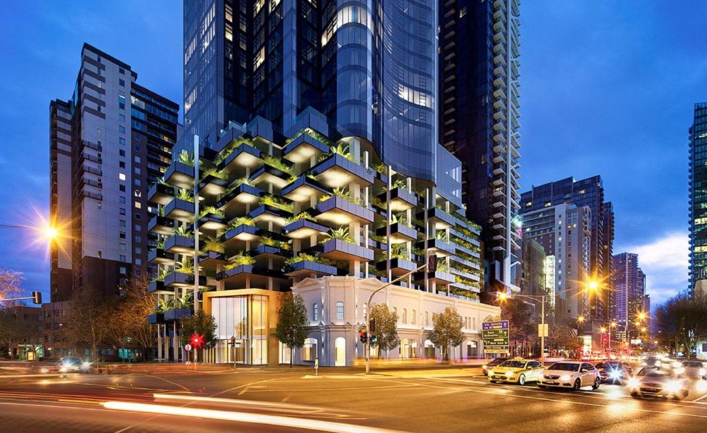 墨尔本CLLIX Australia 108 Apartments的一座高大的建筑,有汽车停在城市里