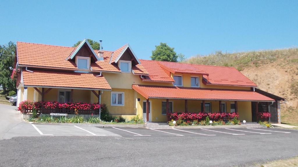 拉科维察巴弗力克公寓酒店的停车场里一座有橙色屋顶和鲜花的建筑