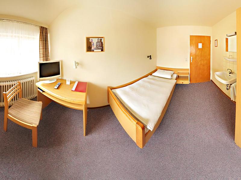 斯图加特潘森克那申酒店的配有一张床、一张桌子和一张桌子的酒店客房