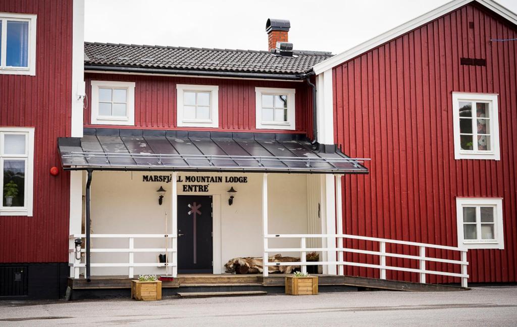 SaxnäsMarsfjäll Mountain Lodge Hotell的一只狗躺在红色建筑的门廊上