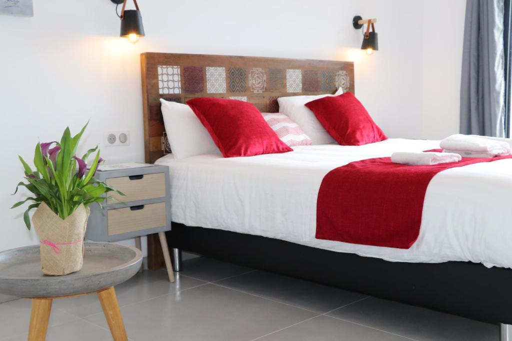 博尼法乔Hotel Fazio的一间卧室配有两张带红色枕头和桌子的床