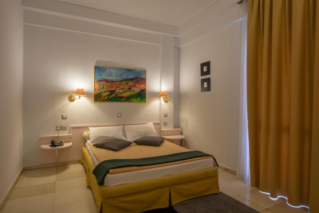 拉里萨大都会酒店的卧室配有一张床,墙上挂有绘画作品
