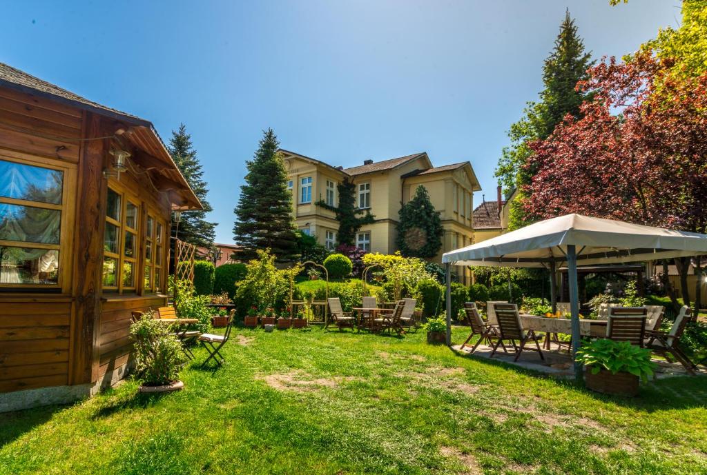 米兹多洛杰威拉杜西亚酒店的一个带椅子和遮阳伞的庭院和一座房子