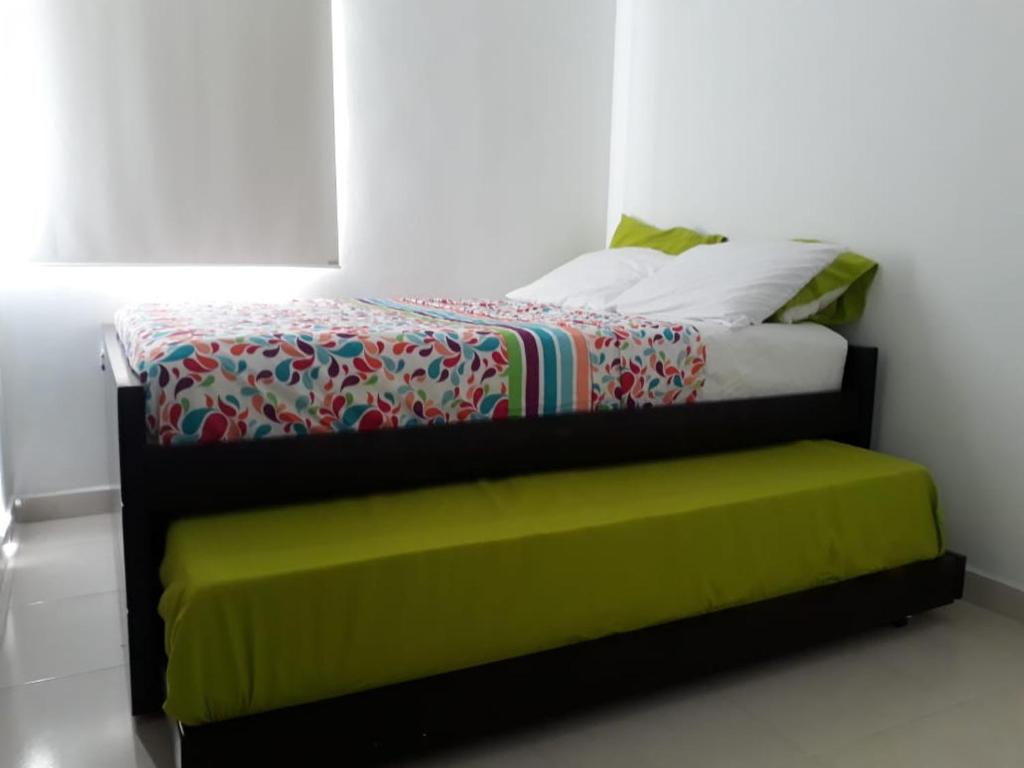 佩雷拉APARTAMENTO AVENIDA CONDINA Primer Piso的一间卧室配有一张床铺,旁边是窗户,设有绿色长凳