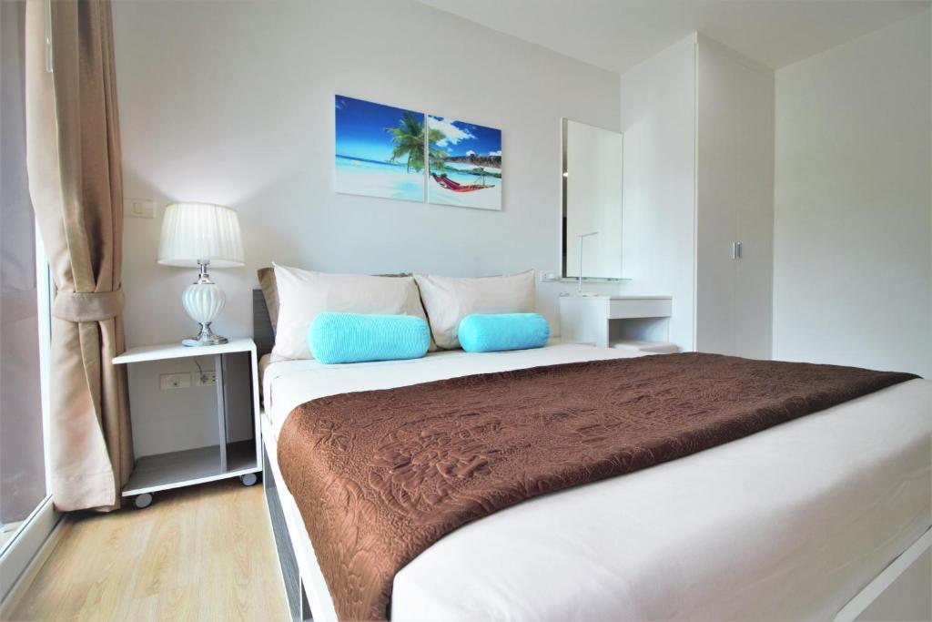 卡塔海滩Ozone Condotel Kata Beach by PHR的白色卧室配有一张带蓝色枕头的大床