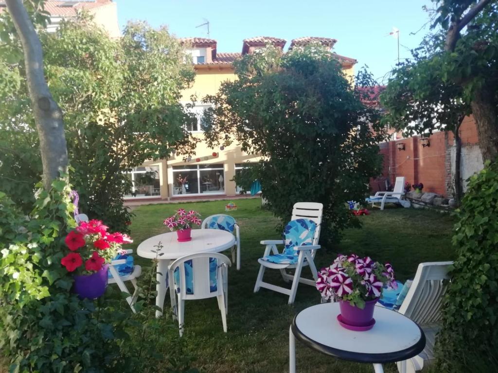 San Andrés del RabanedoBoleta A 5 minutos de León, casa con jardín的花园设有2张桌子和椅子,种有鲜花