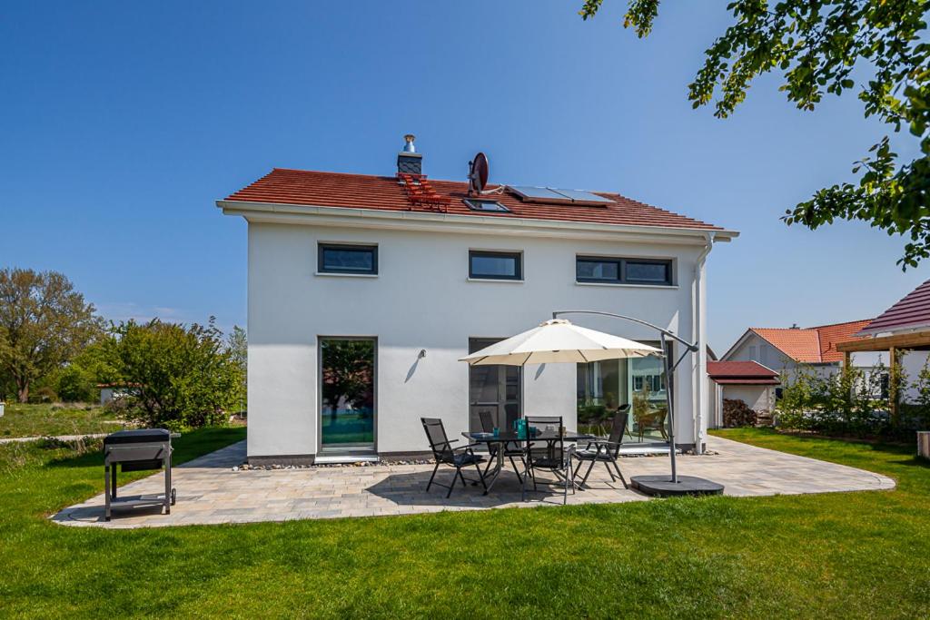 特伦特Ferienhaus Rügen-Relax的白色的房子,配有桌椅和遮阳伞