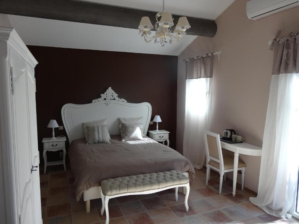 圣雷米普罗旺斯玛斯西姆酒店的一间卧室配有一张床、一张桌子和一个吊灯。