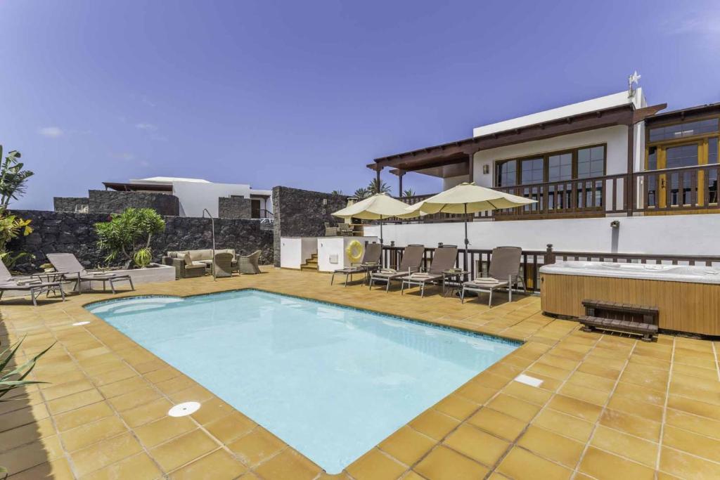 普拉亚布兰卡Villa Azure - LH122 By Villas Now Ltd的一个带椅子的游泳池以及一座房子
