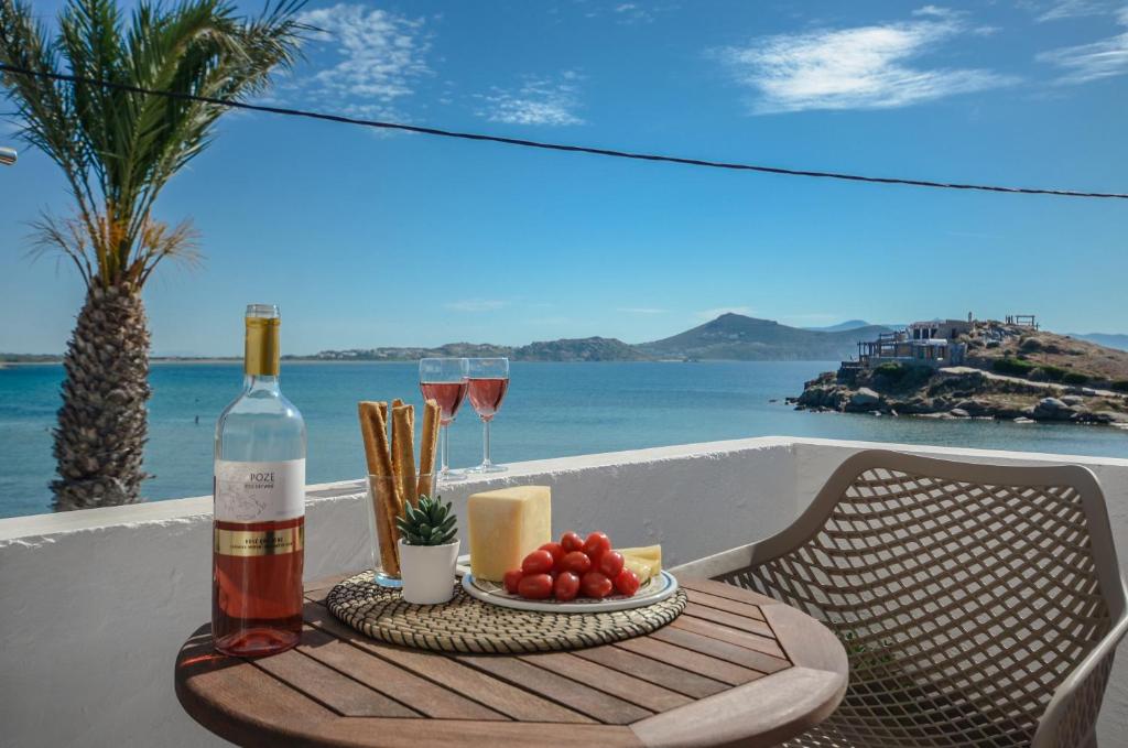 纳克索乔拉Prestige on the beach的一张桌子,上面放着一瓶葡萄酒和一盘水果